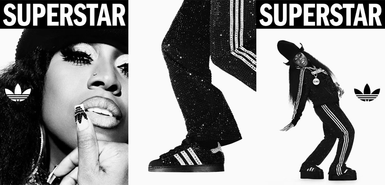Zapatillas Adidas Superstar negras con rayas blancas; el modelo lleva un chándal negro con lentejuelas y acentos de pedrería, además de un sombrero grande.