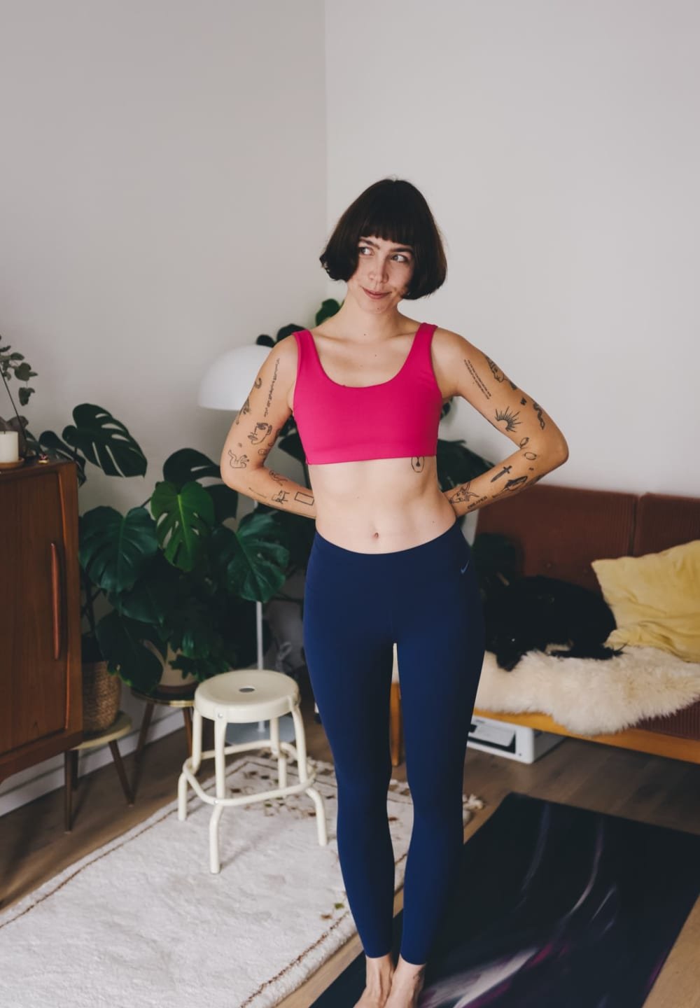 Pink sports bra paired with navy leggings. The bra has a wide neckline and fitted design; the leggings are form-fitting with a logo detail.