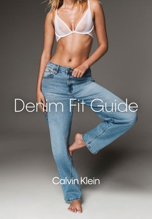 Kvinde iført lyseblå straight-leg jeans og en hvid gennemsigtig bh, stående barfodet med det ene ben bøjet. Teksten lyder: Denim Fit Guide.