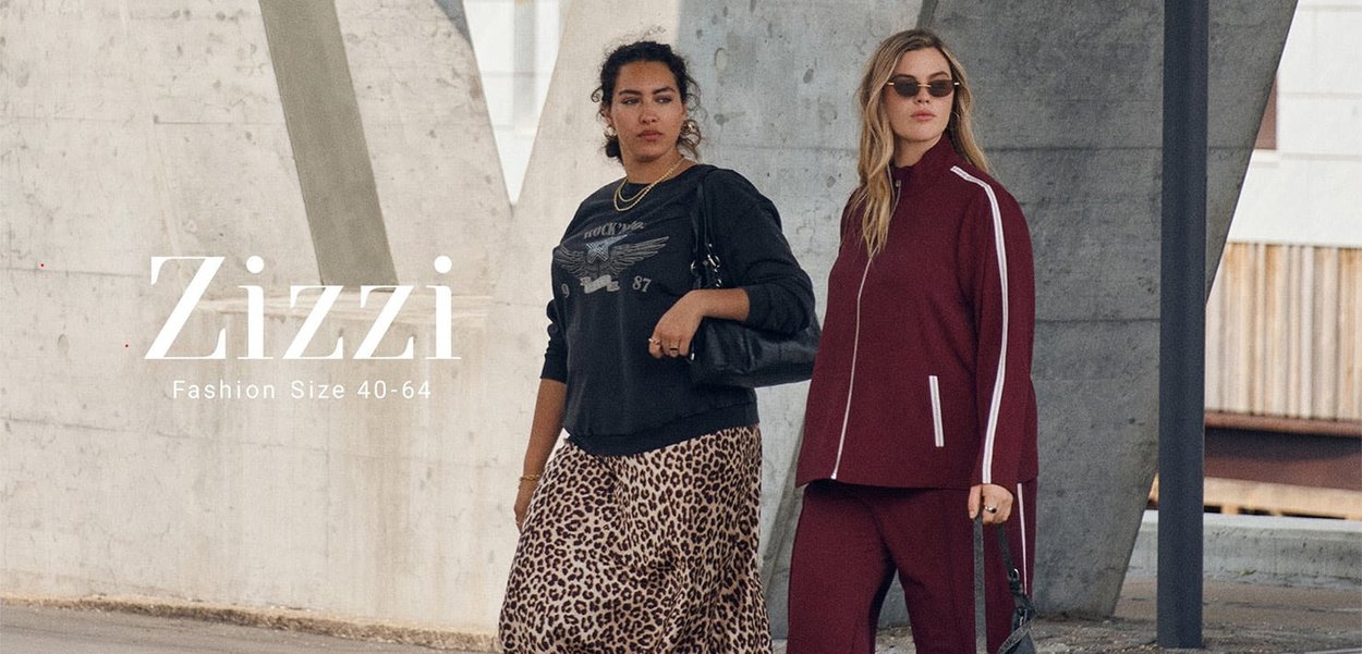 Two women walking outdoors, one in a black sweatshirt and leopard skirt, the other in a burgundy tracksuit with sunglasses, under concrete structure.