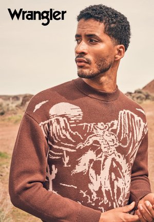 Brun strikkegenser med et kremfarget grafisk motiv av en cowboy som rir på en hest, med ribbet halslinning og mansjetter.