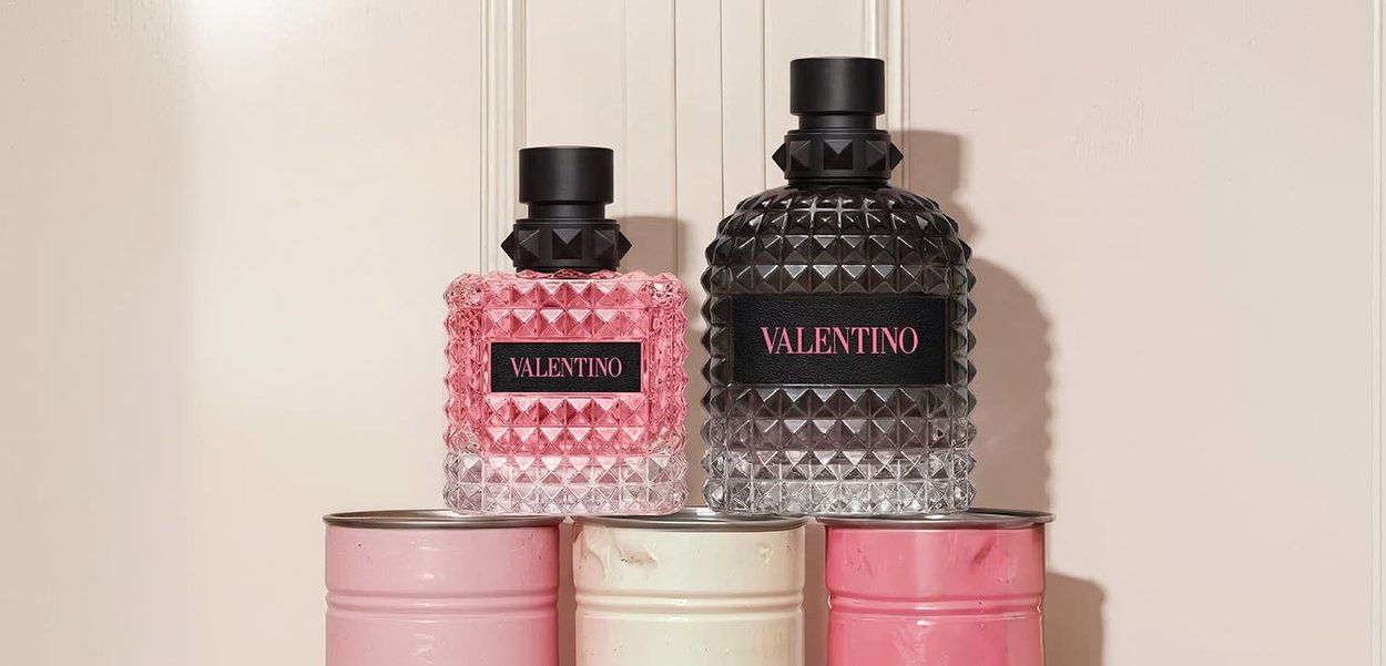 Zwei strukturierte Valentino-Parfümflaschen, eine rosa und eine schwarze, auf drei pastellfarbenen Metalldosen vor hellem Hintergrund platziert.