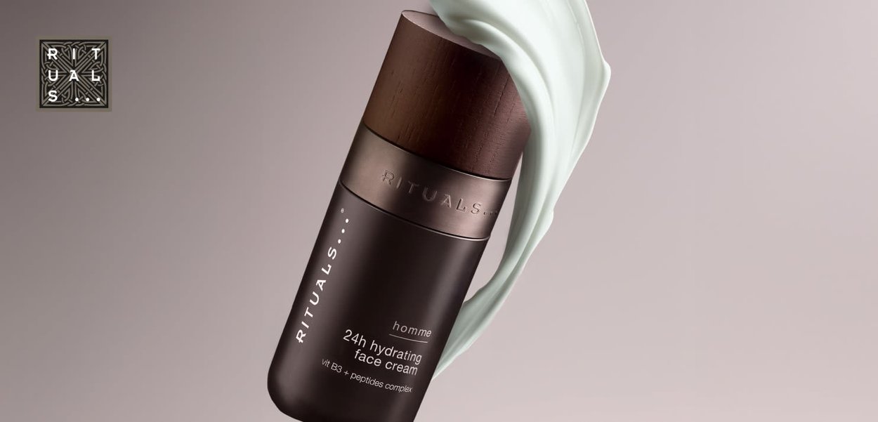 Crème hydratante 24h pour le visage dans un contenant cylindrique noir avec un couvercle en bois. Produit crémeux de couleur vert clair tourné à côté.