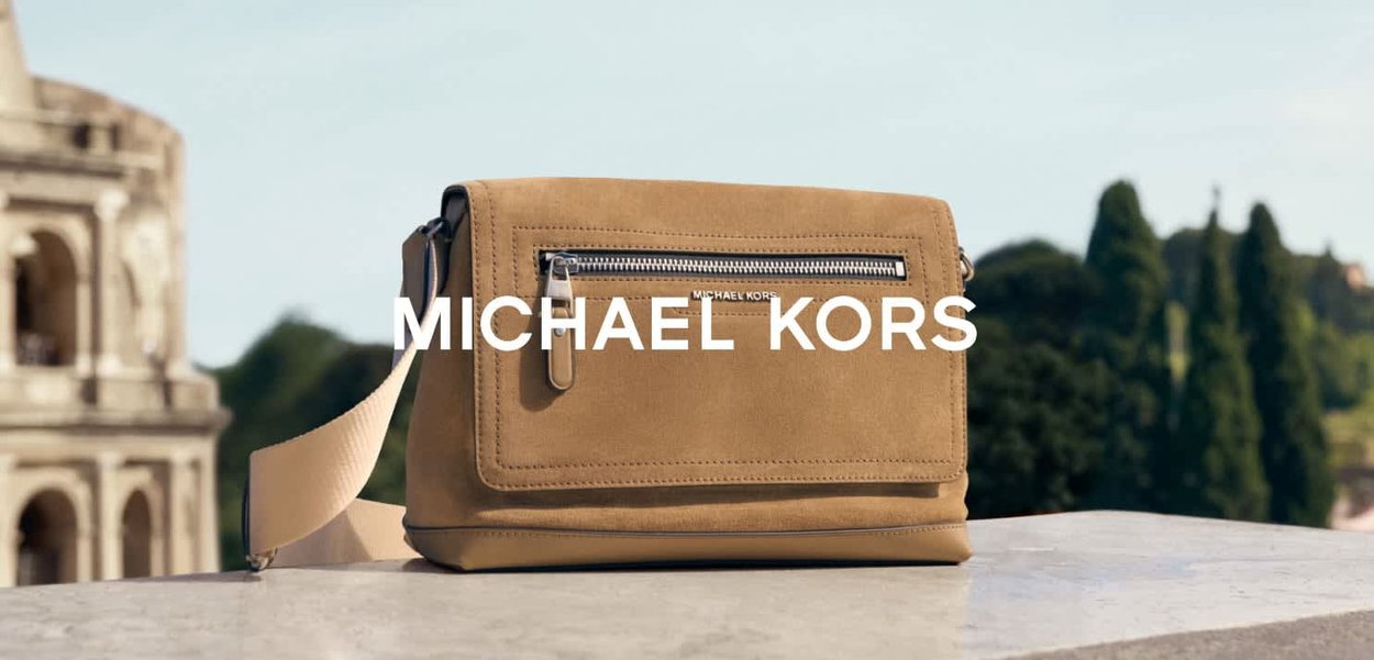 Brun crossbody-väska i mocka med ett framfack med dragkedja, justerbar rem och diskret branding. Mjuk textur och minimalistisk design.