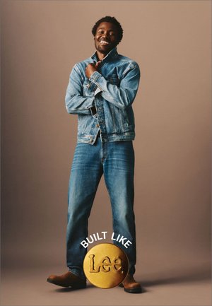 Jeansjacka och jeans i ljusblått, med en klassisk knapppdesign. Bruna stövlar med en cirkulär guld Lee-logotyp och text nedanför.