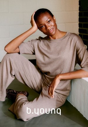 Beige Strick-Loungewear-Set mit einem Rundhalsausschnitt und lockeren Hosen. Weicher Stoff, entspanntes Design und minimale Nähte.