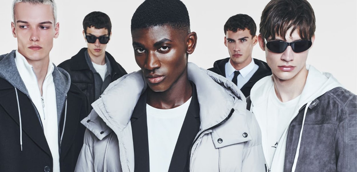 Gruppo di cinque uomini che indossano vari capispalla e occhiali da sole. Le texture includono giacche grigie imbottite, giacche scure e un hoodie bianco.