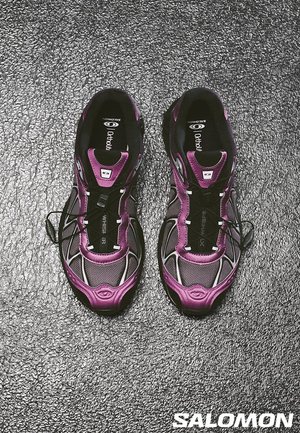 Scarpe da ginnastica nere e viola con tomaia in rete, superfici texturizzate e sistema di lace rapido; logo Salomon visibile sulle solette.