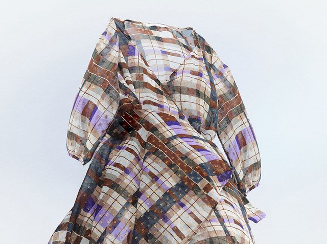 Transparent, patterned dress with short sleeves. It features a checkered design in blue, brown, and white with metallic accents, showcasing a flowing silhouette.