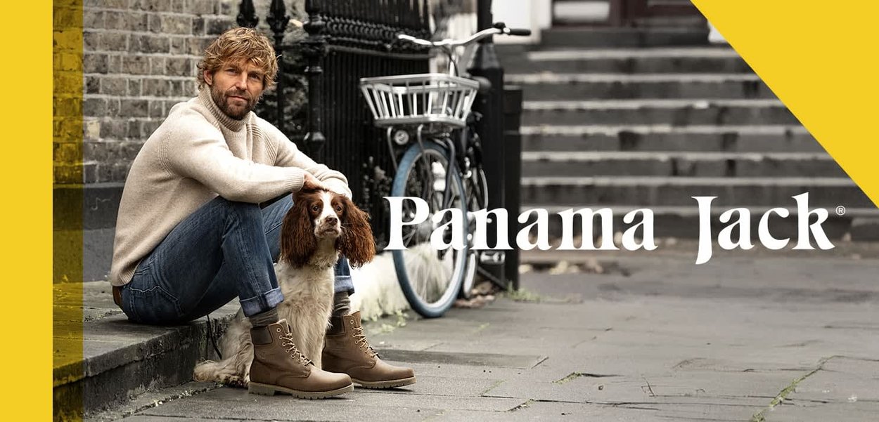 Tan leather hiking boots with laces, paired with blue jeans and a cream sweater, sitting on steps with a brown dog and bicycle nearby.