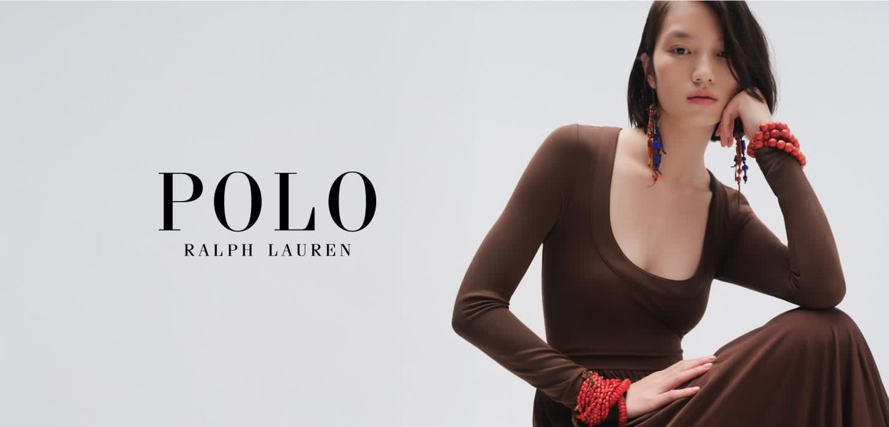 Bruine jurk met lange mouwen en een ronde hals, gecombineerd met rode kralenarmbanden en oorbellen. Eenvoudige achtergrond met merknaam "Polo Ralph Lauren."