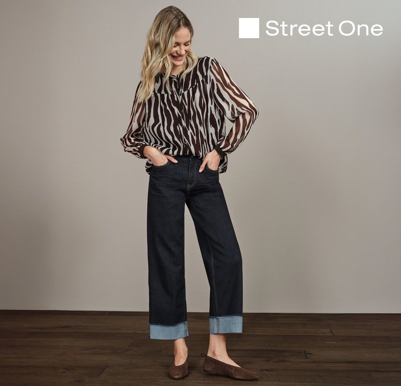 Blus med zebramönster i brunt och kräm, avslappnad passform, i kombination med mörka denimbyxor med vida ben och lätt denimuppvik. Bruna flats kompletterar outfiten.