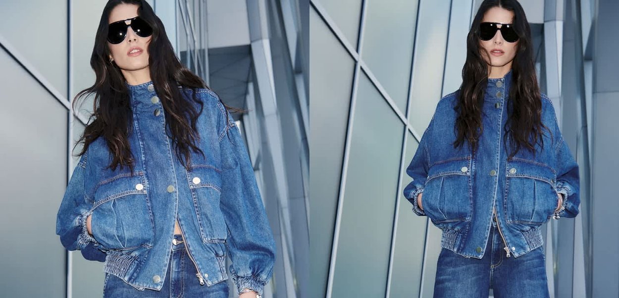 Denim jacket with a boxy design, oversized pockets, and elastic cuffs. Worn with matching jeans, featuring a mid-blue wash and structured silhouette.