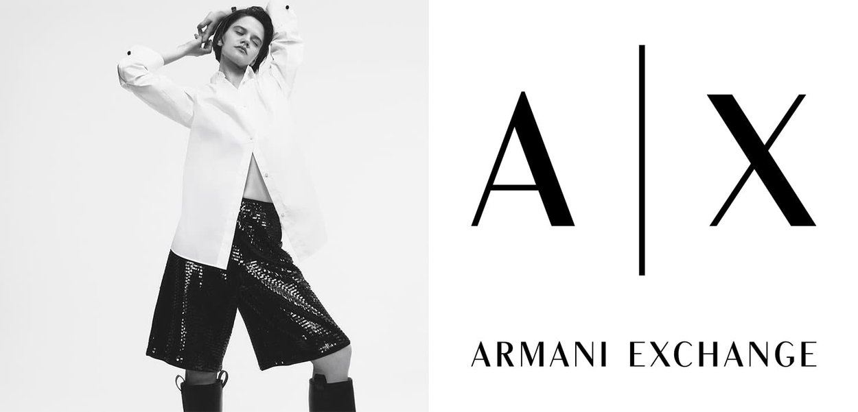 Modèle portant une chemise blanche à boutons surdimensionnée et un short noir pailleté, associé à des bottes noires jusqu'aux genoux. Logo d'Armani Exchange inclus.