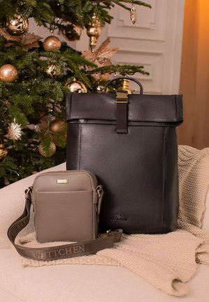 Dwie skórzane torby: duży czarny plecak z klapką oraz mała beżowa torba na ramię z paskiem, obie z ozdobami w kolorze złotym.