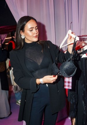 Schwarzer Spitzen-BH mit Bügel und verstellbaren Trägern, an einem Bügel präsentiert. Der Stoff zeigt ein Blumenmuster und ist halbtransparent.