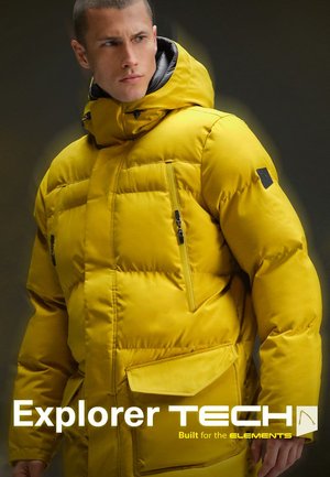 Gele gewatteerde jas met een hoge kraag, voorzakken met rits en een zwart logo op de schouder. Nette, waterafstotende stof.