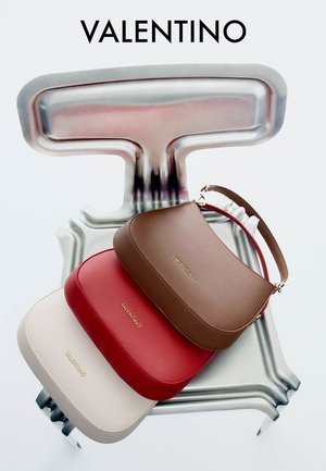 Tre borse in pelle Valentino di colore beige, rosso e marrone disposte verticalmente su una scultura astratta metallica.