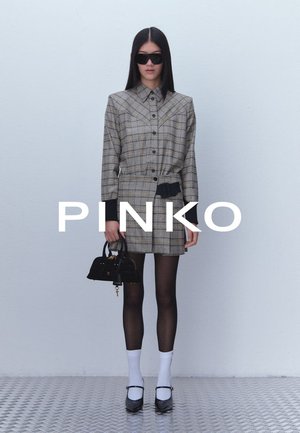 Plaid shirt dress in beige and brown, cinched at the waist with a black belt. Accessories include a small black bag and white socks with shoes.