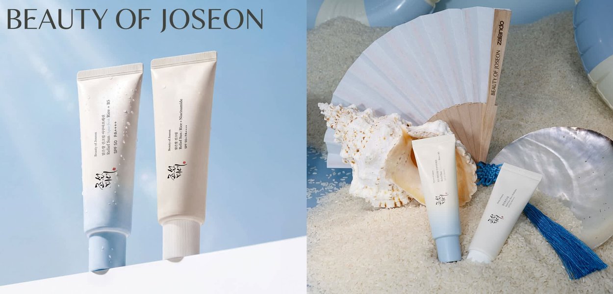 Twee Beauty of Joseon huidverzorgingsbuisjes met Koreaanse tekst, getoond tegen blauwe achtergronden en weergegeven op zand met schelpen en een waaier.