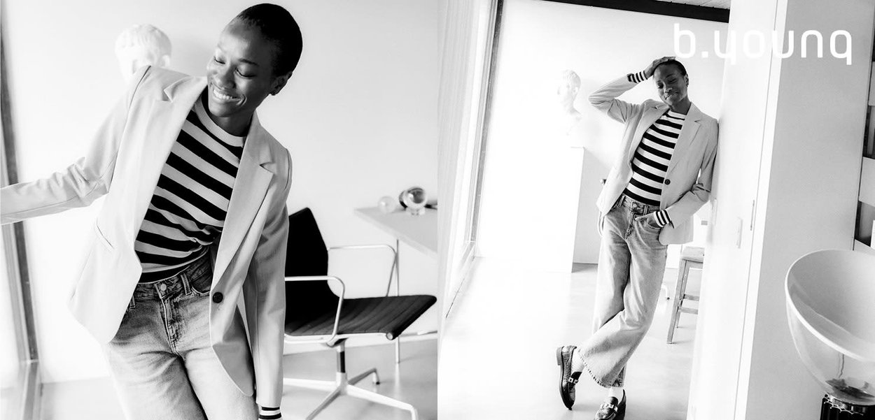 Gray blazer over a black-and-white striped top, paired with light denim jeans and black shoes, in a bright indoor space.