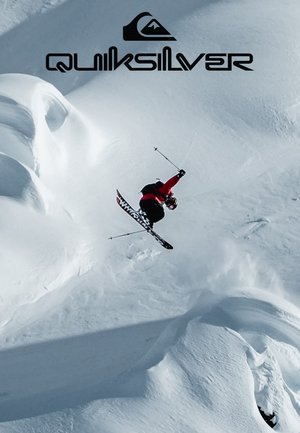 Skifahrer in roter Jacke führt einen Sprung in der Luft über eine verschneite, kurvige Landschaft aus. Schwarze und weiße Skier mit markanten Mustern. Quiksilver-Logo darüber.