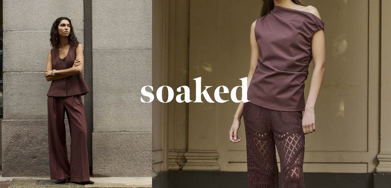 To kvinder modellerer brune outfits stående mod neutrale urbane og arkitektoniske baggrunde med ordet soaked centreret mellem dem.