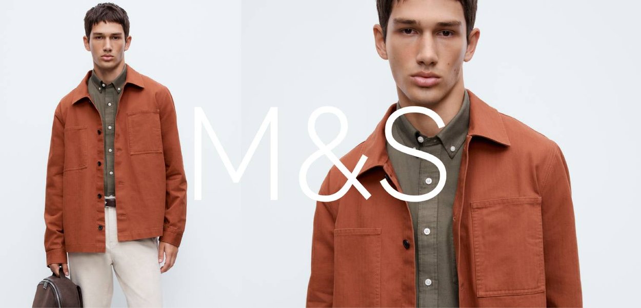 Bawełniana kurtka w kolorze rdzy z dwoma przednimi kieszeniami, noszona na zielonej koszuli zapinanej na guziki. W lewej ręce trzymana jest brązowa skórzana torba.