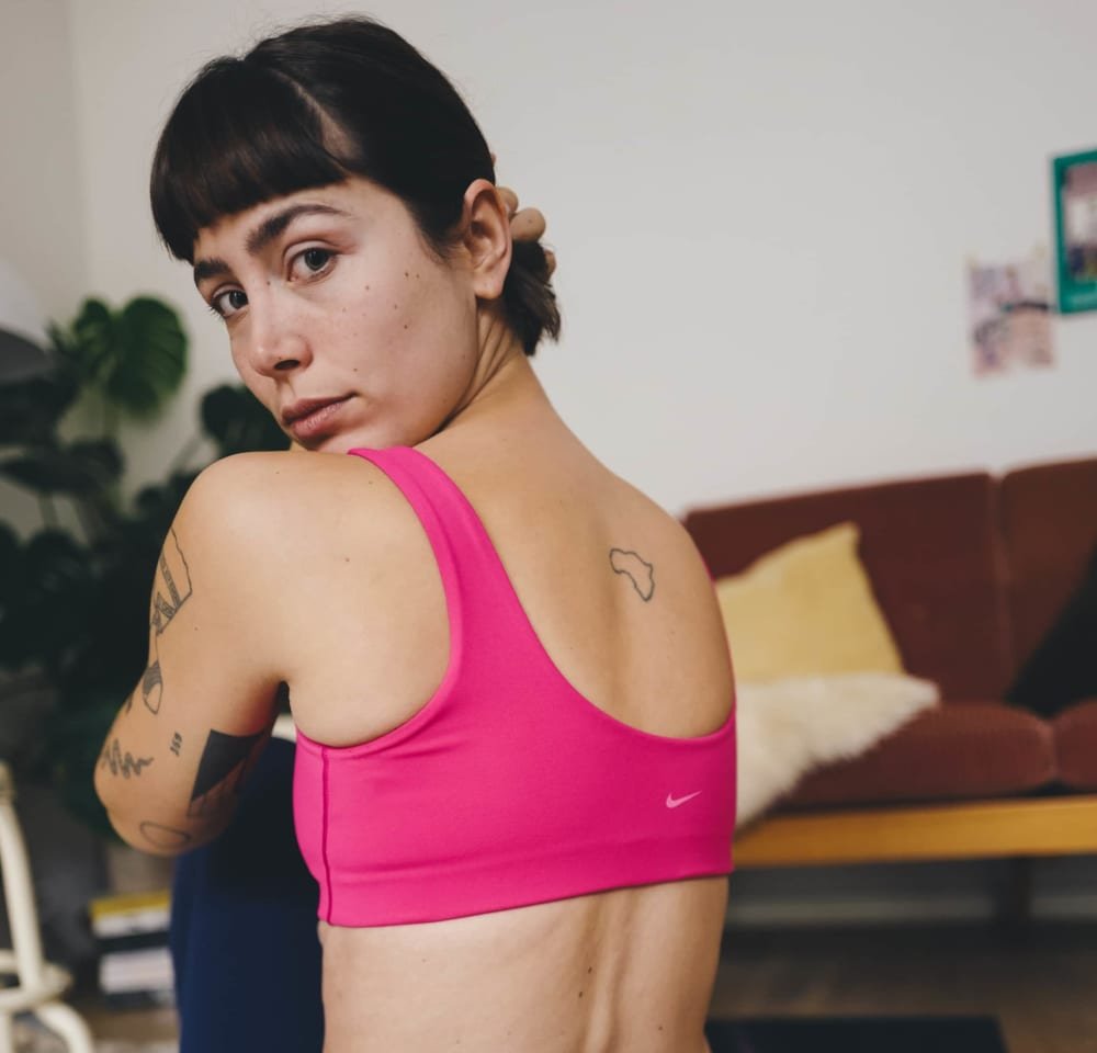 Pink sports bra made of stretchy fabric, featuring a scoop neckline and wide straps, with a small white Nike logo on the front.