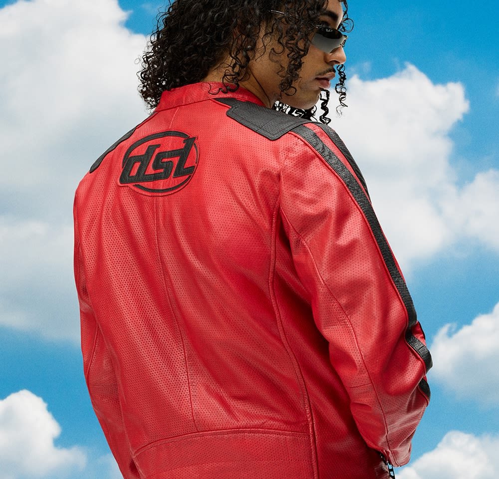 Rode leren motorjack met geperforeerde textuur, zwarte schouderaccenten en logodetail op de achterkant. Bewolkte lucht op de achtergrond.