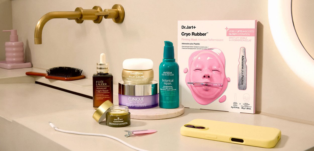 Produkty do pielęgnacji skóry, w tym serum Estée Lauder, krem Darphin, balsam Clinique, serum Aveda, krem pod oczy Origins oraz ujędrniająca maska Dr.Jart+ Cryo Rubber na łazienkowym blacie.