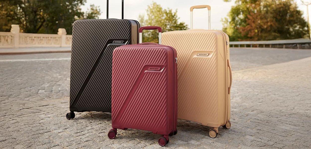 Trzy walizki w kolorach czarnym, burgundowym i jasnobrązowym, z teksturowanym diagonalnym wzorem, solidnymi kołami i wysuwanymi uchwytami.