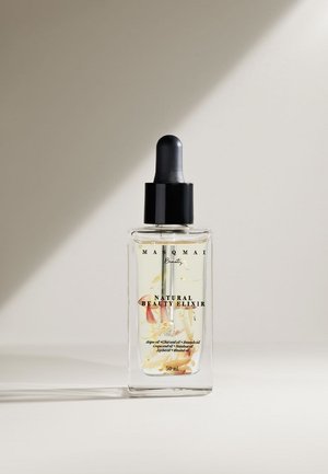 Duidelijke glazen fles met een zwarte pipetdop, waarin een lichtgele olie met drijvende bloementelementen zit. Etiket leest "Natuurlijk Schoonheidselixir." 50 ml.