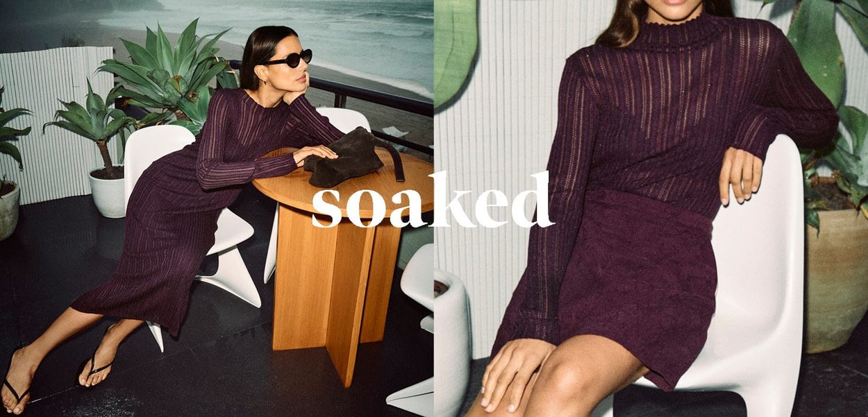 Purple ribbed knit sweater with a mock neck, paired with a matching textured skirt. Models seated near plants, with a minimalist chair and table.