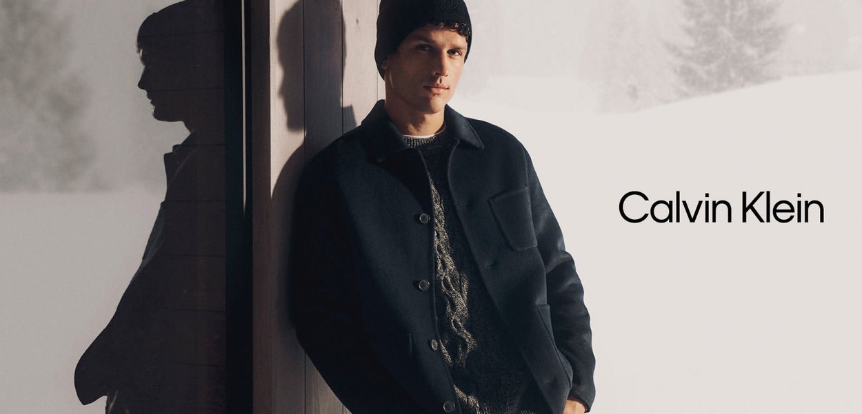 Abrigo de lana azul oscuro para hombre con botones delanteros y bolsillo frontal, usado sobre un suéter claro texturizado, combinado con un gorro de punto oscuro.