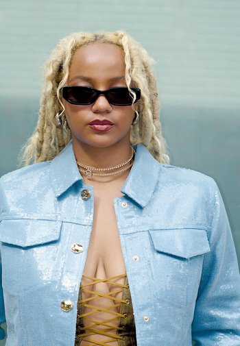 Lichtblauwe sequined jas met een kraagontwerp en gouden knopen; gecombineerd met een gouden korset met een veterdetail.