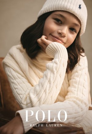 Pull en tricot torsadé crème avec de longues manches et un ourlet côtelé, associé à un bonnet blanc côtelé arborant un petit logo.