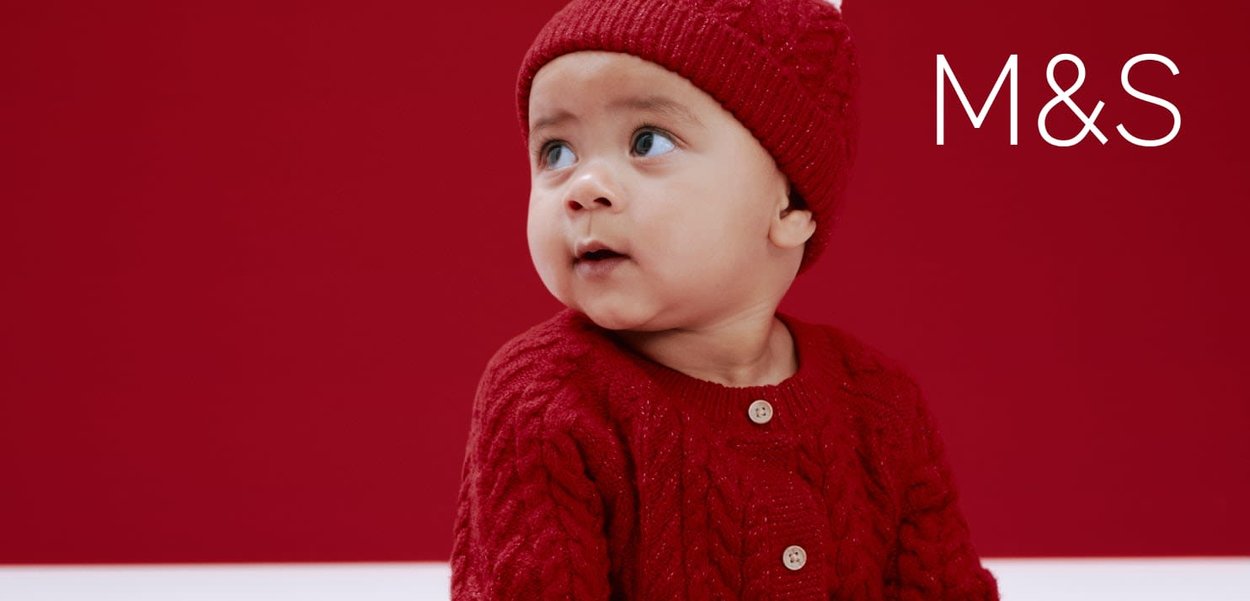 Czerwony dziergany kardigan z ozdobnym wzorem warkoczowym, wyposażony w drewniane guziki, zestawiony z pasującą czerwoną dzierganą czapką beanie.