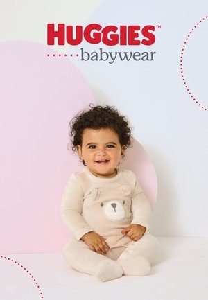 Beiger Baby-Strampler mit langen Ärmeln, vorne mit Bärenkopf-Applikation. Weiche, gerippte Struktur. Hintergrund mit pastellfarbenen Formen.