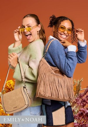 Due donne posano schiena contro schiena, indossando occhiali da sole gialli. Una tiene una borsa a tracolla di un beige chiaro; l'altra porta una borsa marrone con frange.