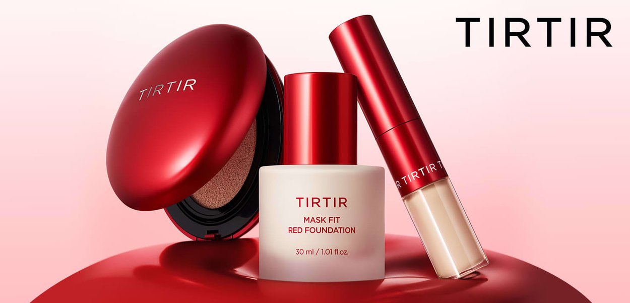 Red cosmetics packaging featuring a round compact, a foundation bottle, and a lip product. Smooth, glossy surfaces with text labels.