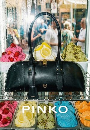 Bolso negro Pinko exhibido detrás de un cristal con tarrinas de helado de colores cubiertas con frutas y frutos secos en un bullicioso mercado.