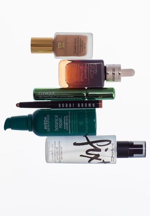 Fondation, sérum de réparation de nuit, mascara, crayon pour les yeux, sérum de réparation botanique et spray fixateur disposés en vue à plat.