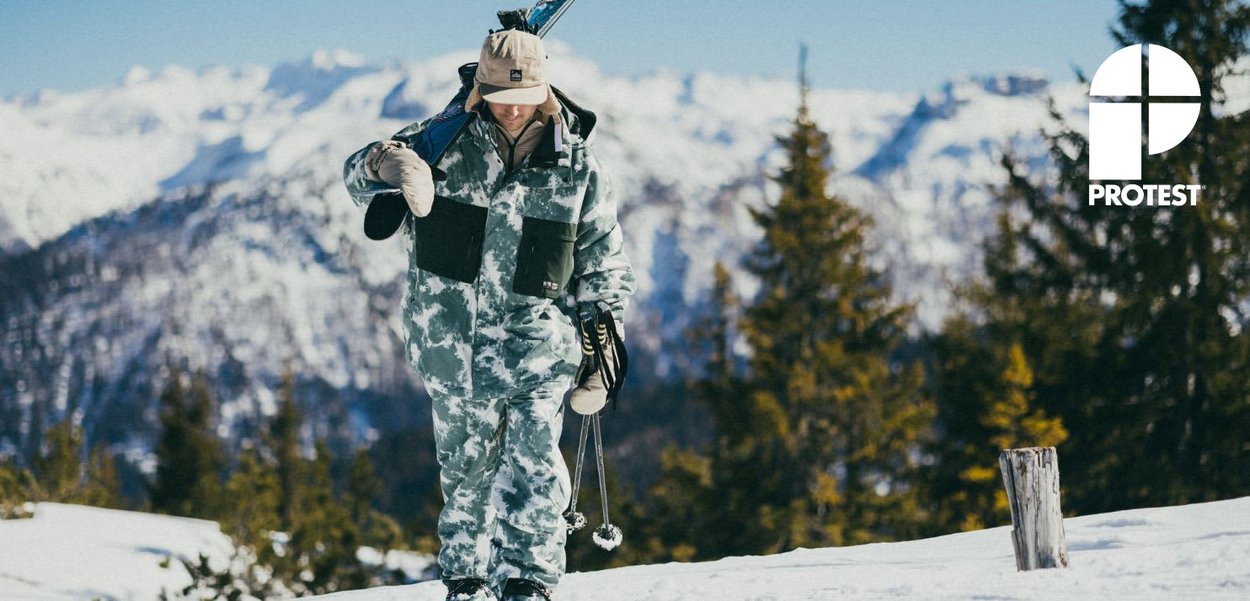 Sneeuwwit camouflagekleding met een capuchon, twee zakken aan de voorkant en skibenodigdheden. Het materiaal lijkt bestand tegen weersinvloeden, geschikt voor winteractiviteiten.