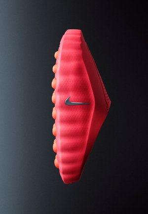 Zapato Nike en rosa brillante con una parte superior texturizada, diseño único en forma de ondas y suela naranja, con un pequeño logo Swoosh plateado.