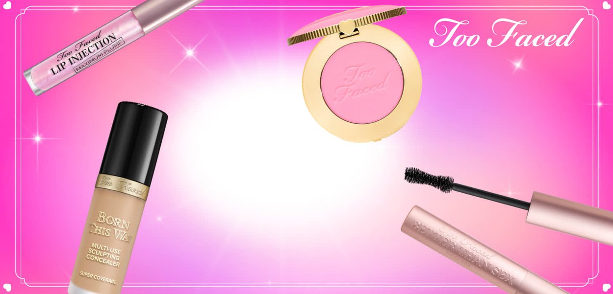 Make-upproducten gerangschikt op een roze achtergrond: een gloss met zwarte tekst, een foundationfles met een gouden etiket, een gouden compact met roze poeder en een mascara tube.