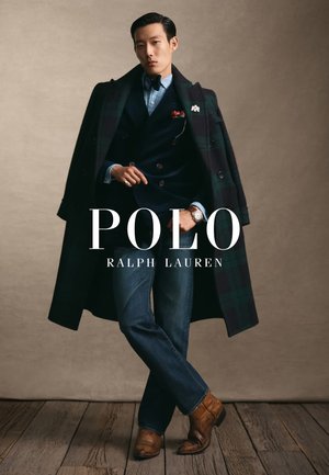 Manteau à carreaux sombres sur un costume bleu marine, chemise bleu clair, jean bleu et bottes marron. Accent notable d'une rose rouge épinglée au manteau.