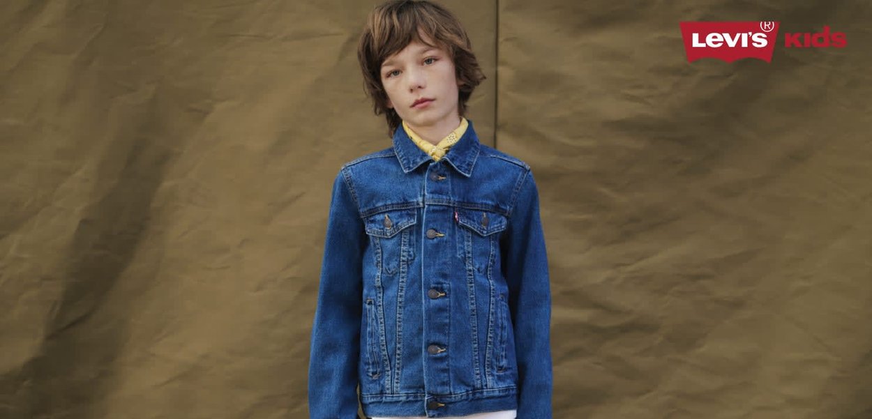 Veste en denim bleue à coupe classique, avec fermeture par boutons, deux poches à rabat, et une texture douce, portée sur une chemise jaune.