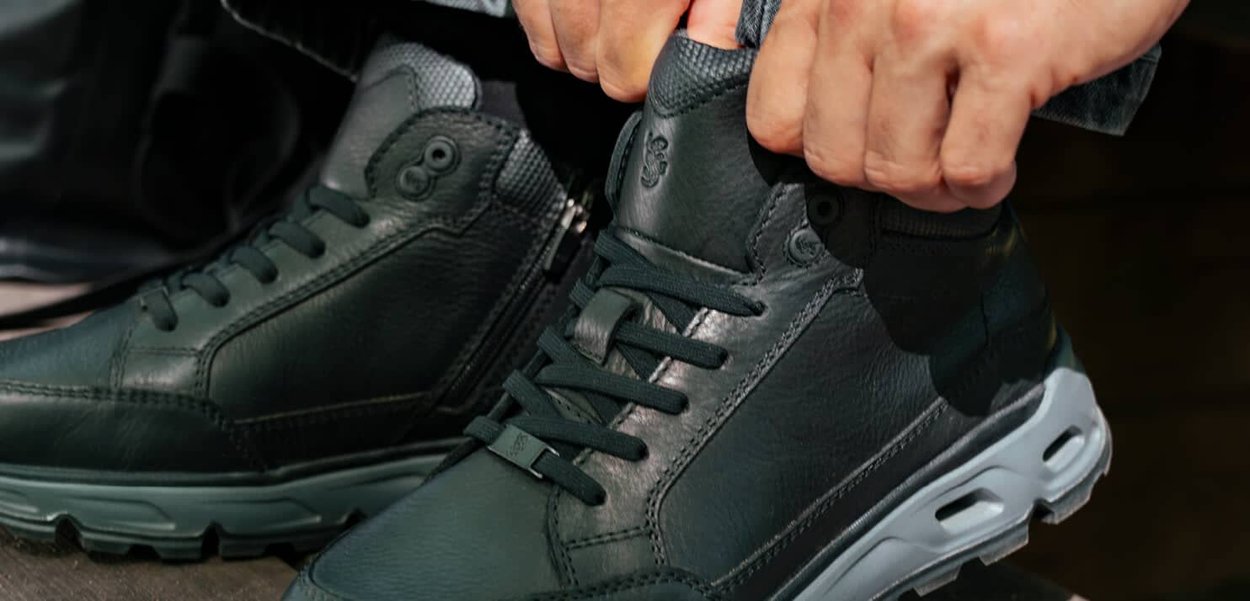 Schwarze Leder-Hochschuhe mit strukturierten Akzenten und einem gepolsterten Kragen, ausgestattet mit Schnürung und einer kontrastierenden grauen, klobigen Sohle.