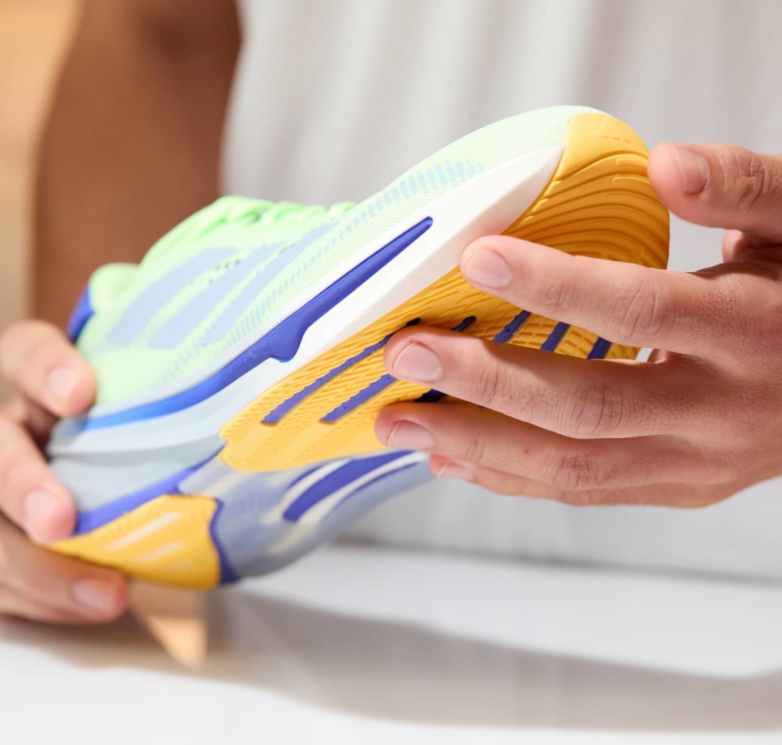 Hellgrüner Laufschuh mit blauen und gelben Akzenten. Verfügt über ein strukturiertes Obermaterial und eine flexible Sohle mit einem gewellten Profil.